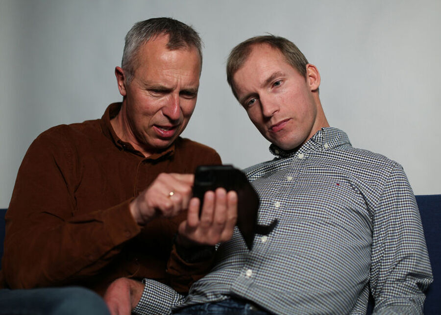 En mann hjelper en annen med mobiltelefonen