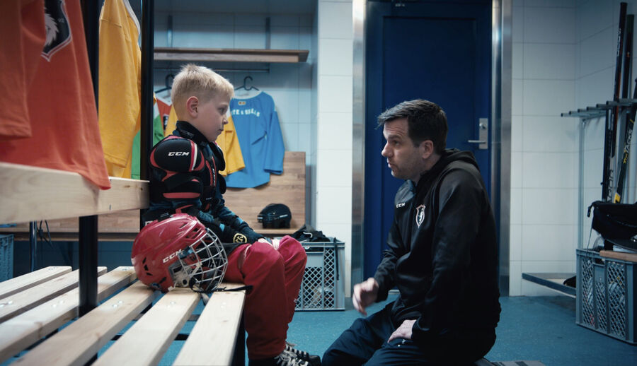 bekymret mann og gutt snakker i garderobe, ishockey