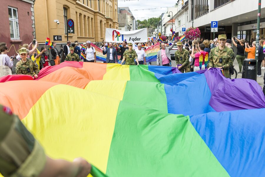 Det var god stemning i Markens under Skeive Sørlandsdager i 2021. (Foto: Kjell Inge Søreide) Mennesker i handlegate som holder et stort regnbueflagg mellom seg