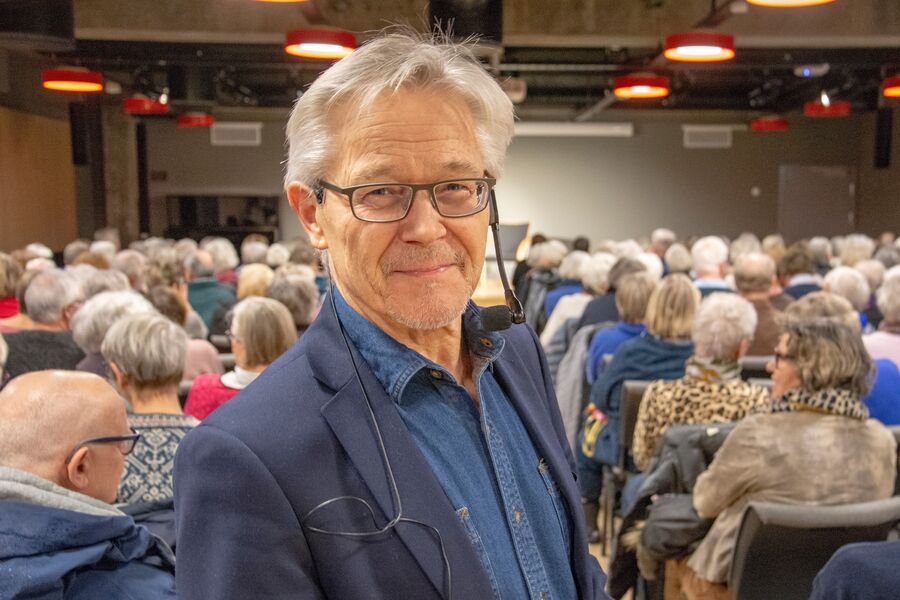 Portrett av mann med mange tilhørere som sitter på stolrekkene bak